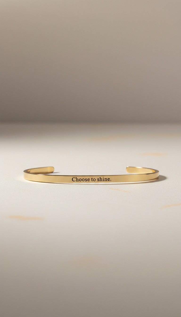 KM Jewelry Co. engraved gold bangle in 18K gold PVD stainless steel with "Choose to shine." inscription. Simple, polished design.