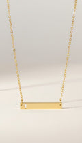 KM Jewelry Co. 18k gold plated hollow cross bar necklace with a delicate, minimalist design.