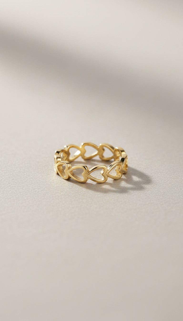 KM Jewelry Co. 18K gold PVD stainless steel ring with a continuous pattern of open hearts.